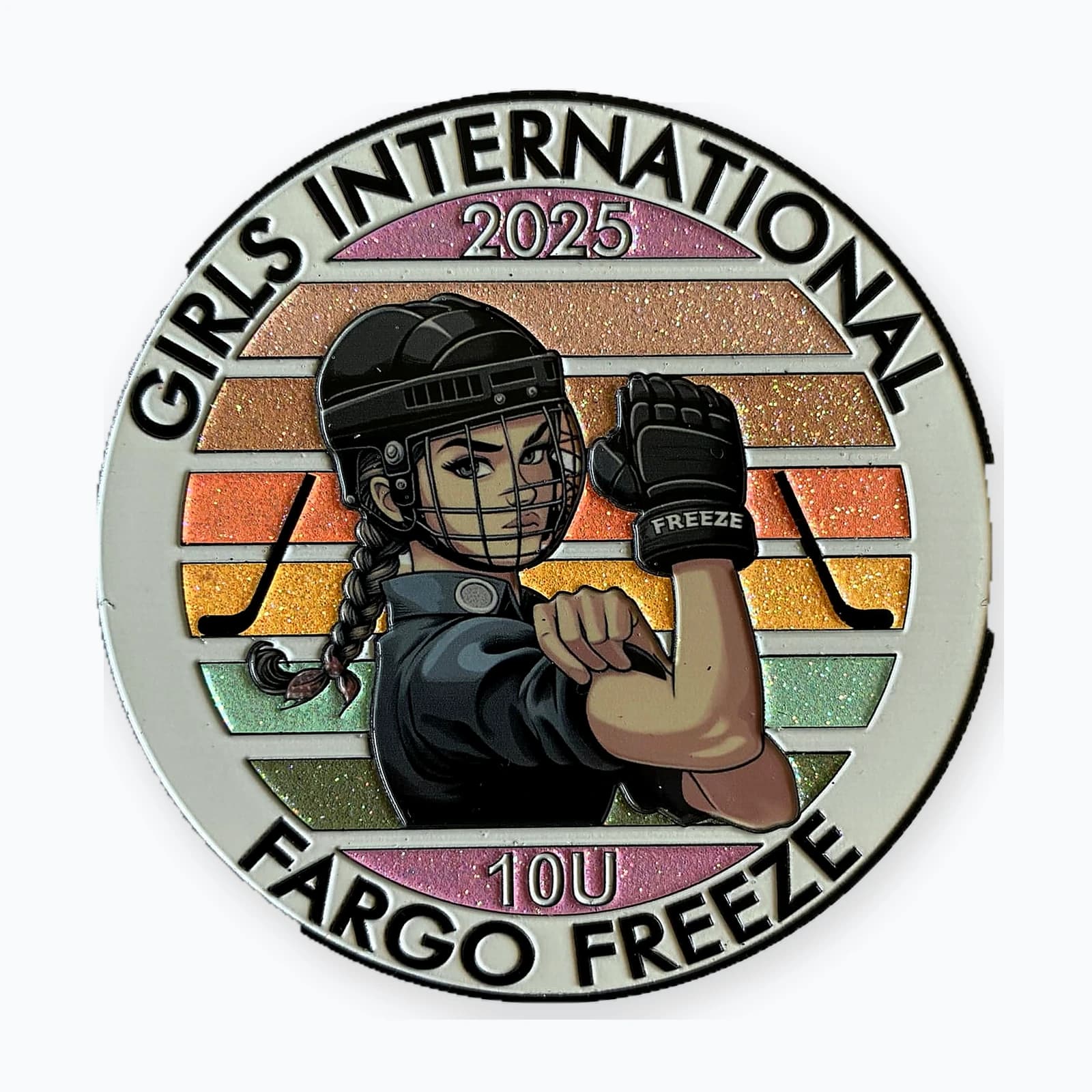A round Girls International trading pin for a Fargo Freeze 10U team, showing a girl player flexing against a striped glitter background