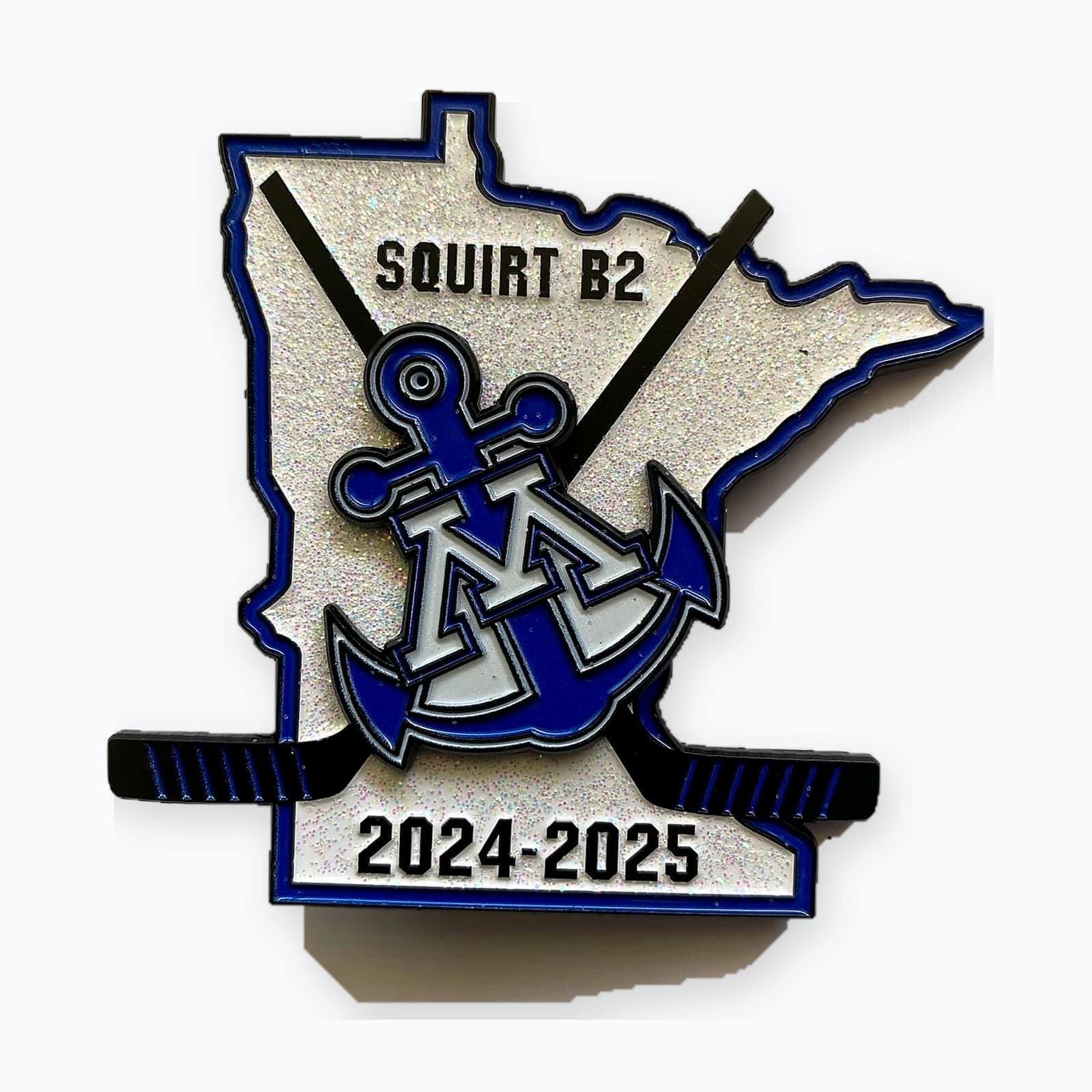 A Minnesota-shaped trading pin with an anchor and crossed hockey sticks