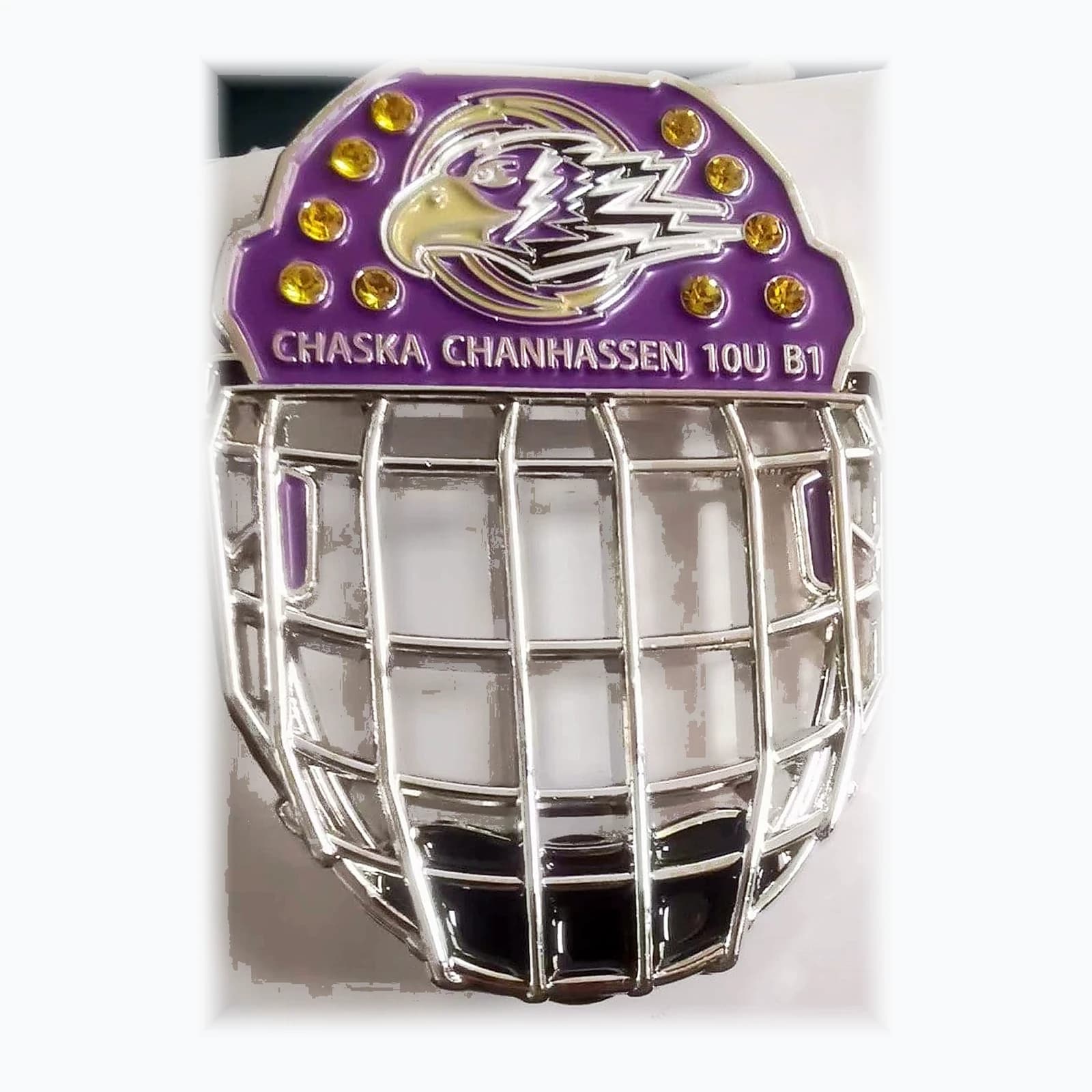 A trading pin shaped like a goalie mask with a see-through cage and set crystals